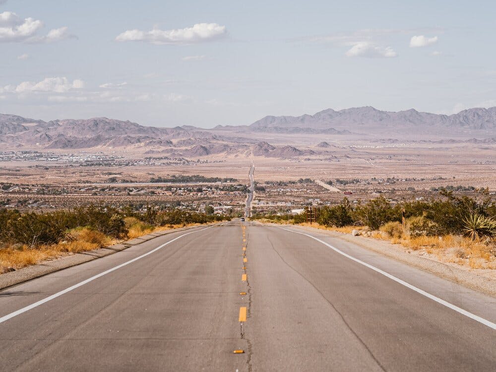 gray_concrete_road_near_green_grass_field_under_white_clouds-scopio-03456e37-a2ae-430d-8af6-ea1e7f2f73c8.jpg