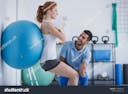 stock-photo-smiling-professional-personal-trainer-helping-sportswoman-exercising-with-ball-1188666193.jpg