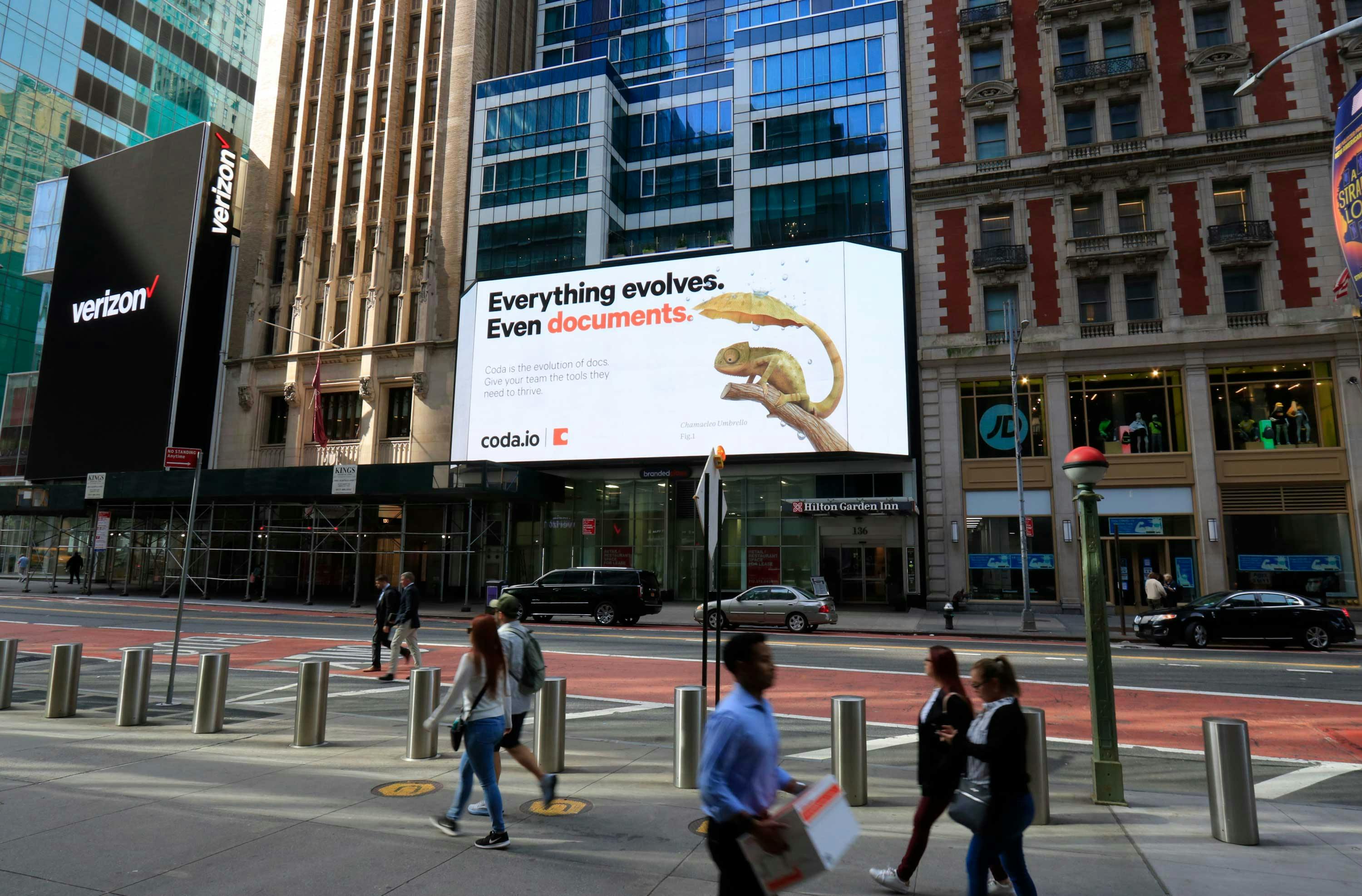 A billboard in NYC - a chameleon with an umbrella tail; a lizard using its umbrella tail to shelter from the rain