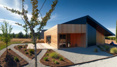 DALL·E 2022-10-28 17.36.52 - ecological house, award winning design, wooden accents, in the middle of a field of sarrazin, with a zen garden.png