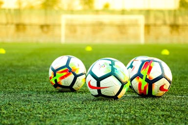 three white-and-black soccer balls on field
