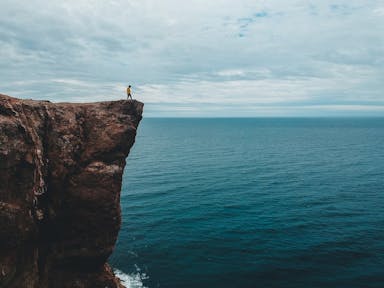 person standing on rock formation near sea during daytime