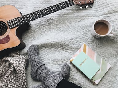 person wearing gray socks near acoustic guitar