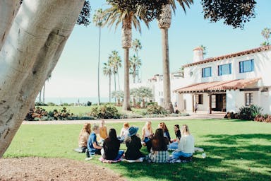 people sitting on ground while forming round during daytime