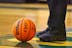 person in black pants and black leather boots standing on basketball court