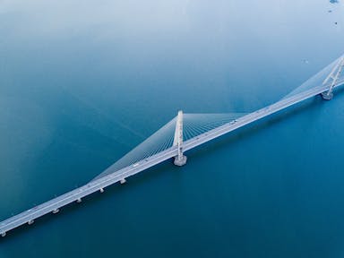 gray concrete bridge on body of water in aerial photography