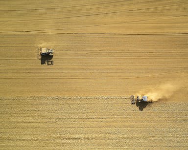 aerial view of two harvesters on brown field