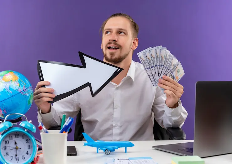 handsome-businessman-white-shirt-holding-white-arrow-showing-cash-looking-aside-with-smile-face-sitting-table-offise-purple-background_141793-53976.jpg