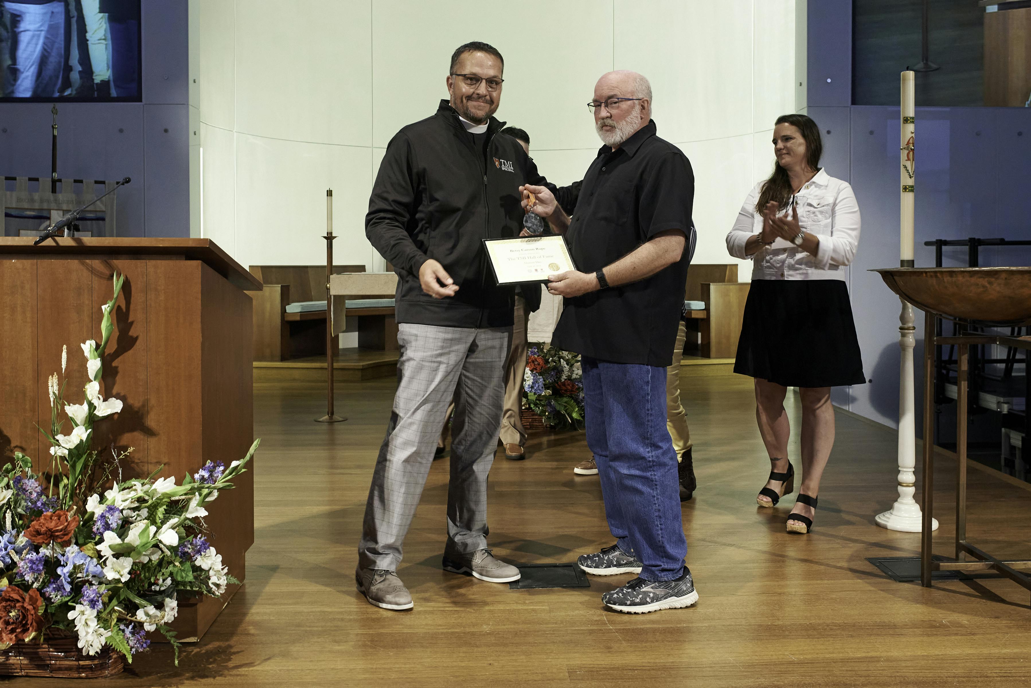 Allan Rupe '80 accepts award for Betsy Rupe from Father Scott.jpg