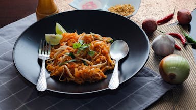 a black plate topped with pasta and vegetables