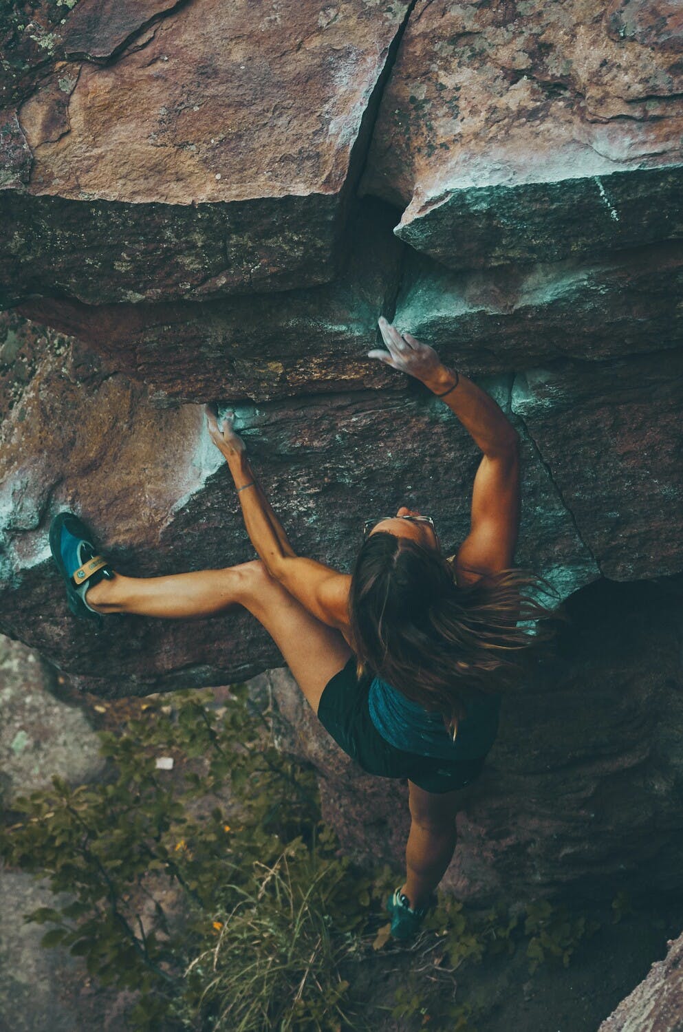 Una mujer escala una pared de rocas sin la ayuda de cuerdas, solo utilizando sus manos y pies.