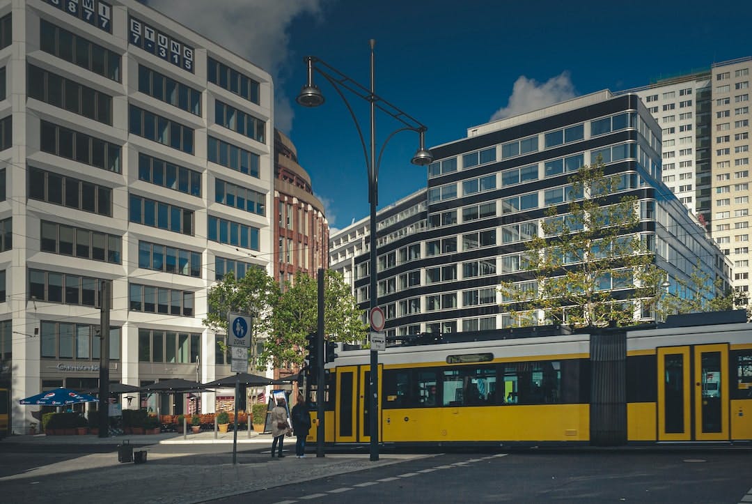 yellow and black tram on road near white concrete building during daytime